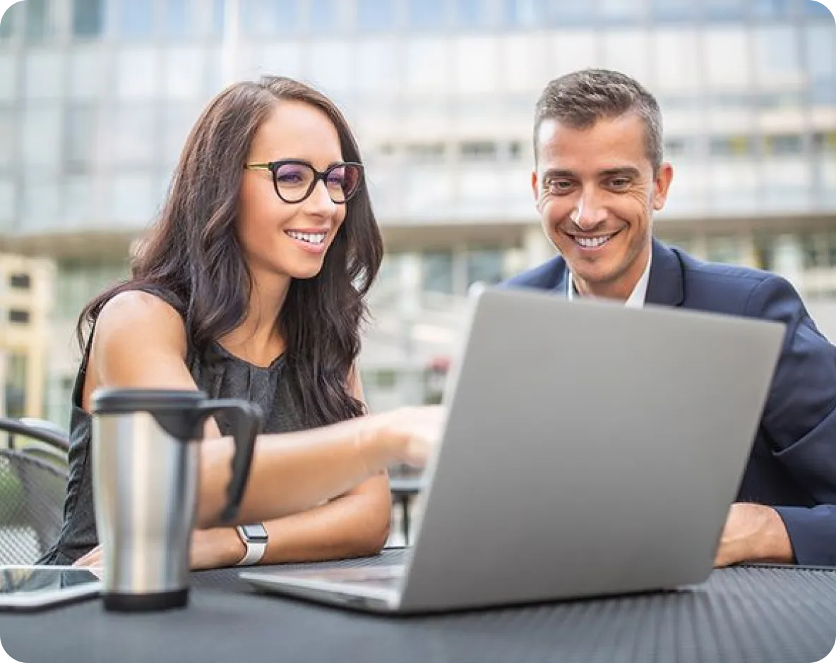 Two professionals smiling at a laptop